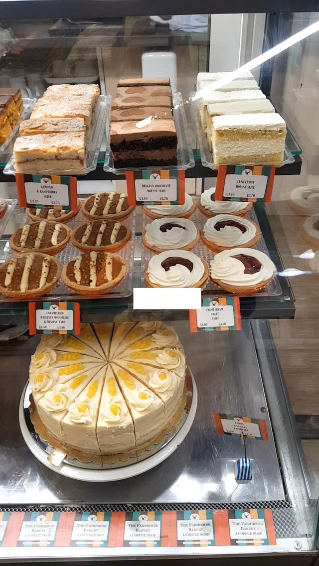 A bakery display cabinet filled with cakes, tarts and slices